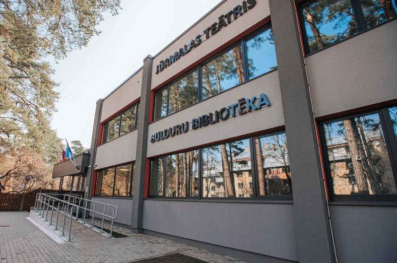 Divstāvīga ēka ar plašiem logiem un rampu. Uz ēkas divi uzraksti "Jūrmalas teātris" un "Bulduru bibliotēka".